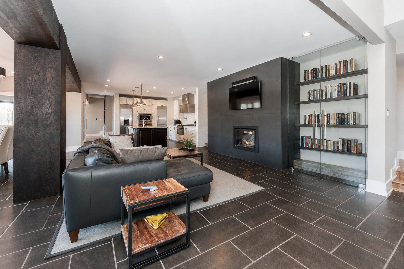 Social room with fireplace, library wall and open kitchen beyond