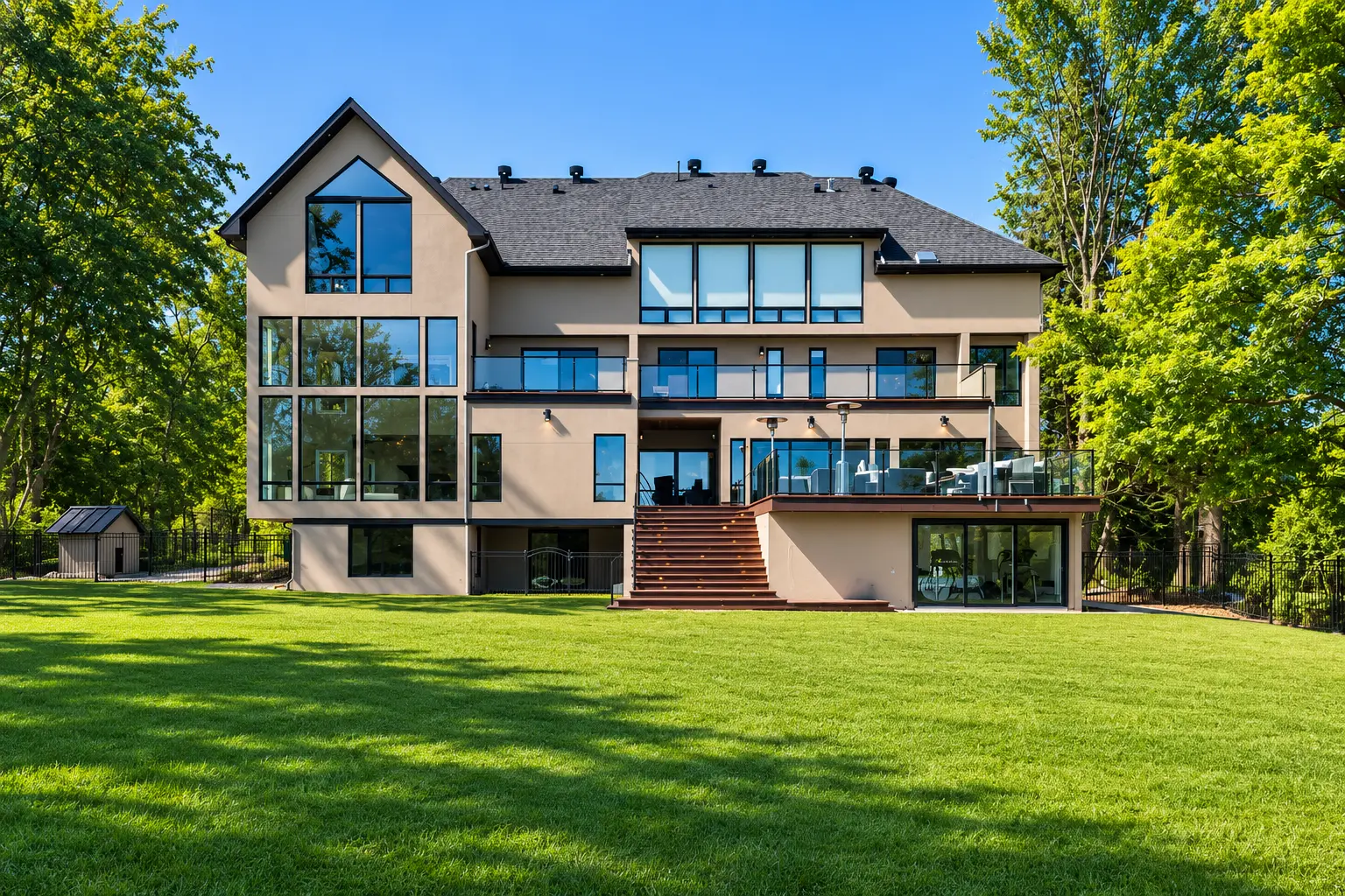 The rear of the house above the lawn, with glass-railed balconies and steps down from the deck